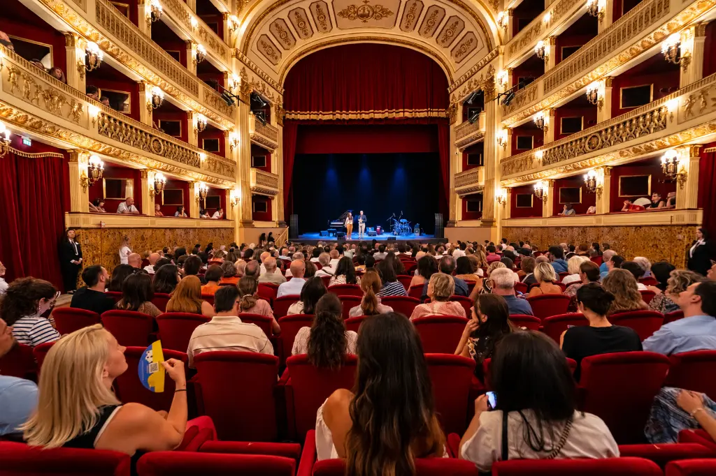 Teatro storico gremito illuminato d’oro.webp