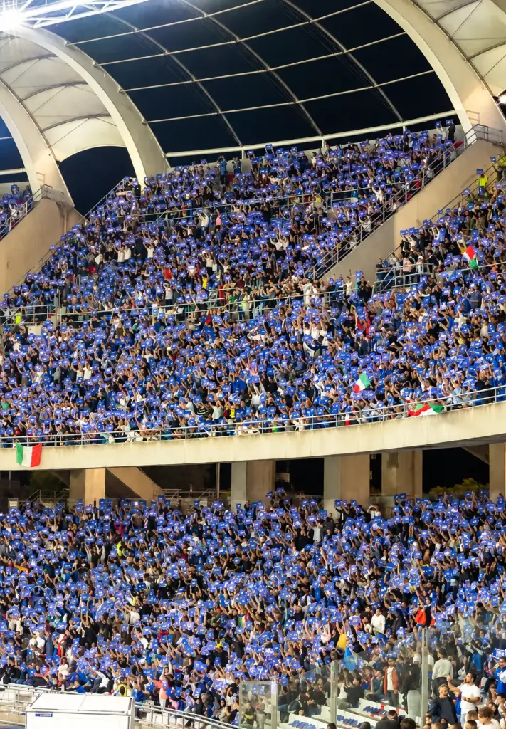 Folla blu sotto gli archi dello stadio.webp